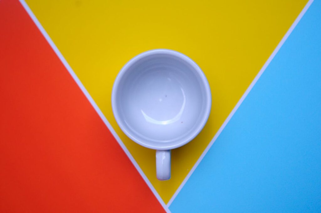 Overhead shot of a white mug on vibrant red, yellow, and blue background. Perfect for design and modern themes.